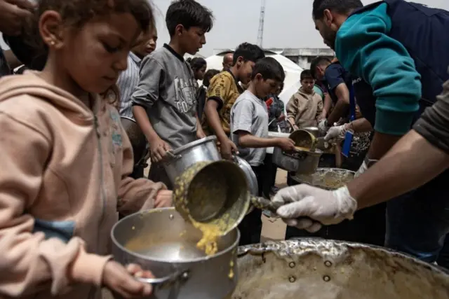 نازحون فلسطينيون يتلقون وجبات الطعام في مخيم جباليا شمال غزة - 8 أبريل/ نيسان 2025. 