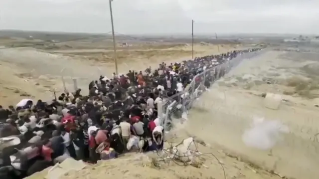 طابور مزدحم من الناس في ممر مسيج بالقرب من موقع لمؤسسة غزة الإنسانية